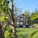 Ein kleines Gewächshaus steht in einem privaten Garten.