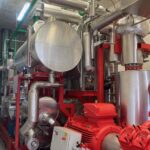 rote und silberne Metallrohre verbinden Behälter, Pumpen und Ventile