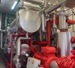 rote und silberne Metallrohre verbinden Behälter, Pumpen und Ventile