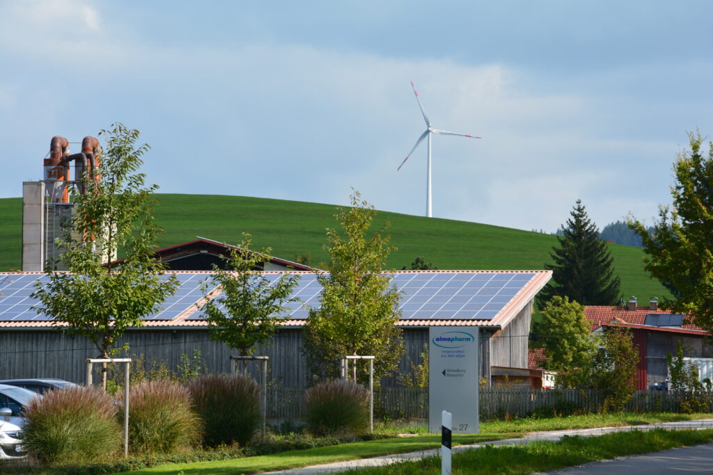 Photovoltaik-Paneele auf einem Gebäude und eine Windenenergieanlage
