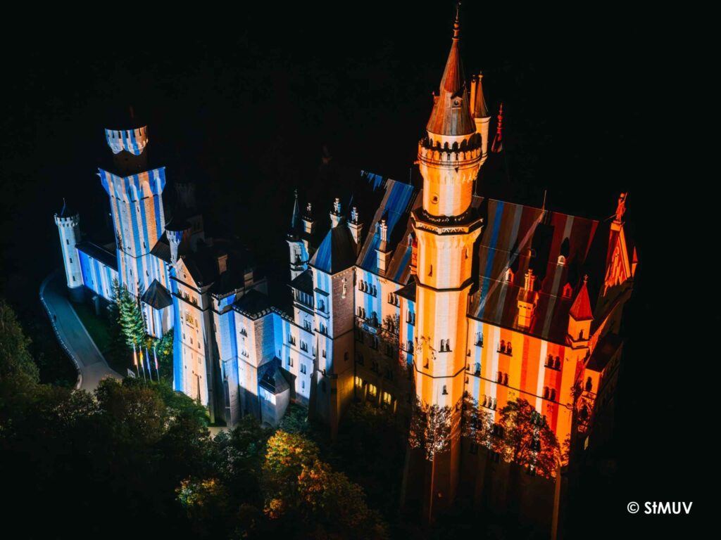 Schloss Neuschwanstein zum Auftakt der Bayerischen Klimawoche 2026 mit den Bayerischen Klimastreifen illuminiert, Copyright StMUV
